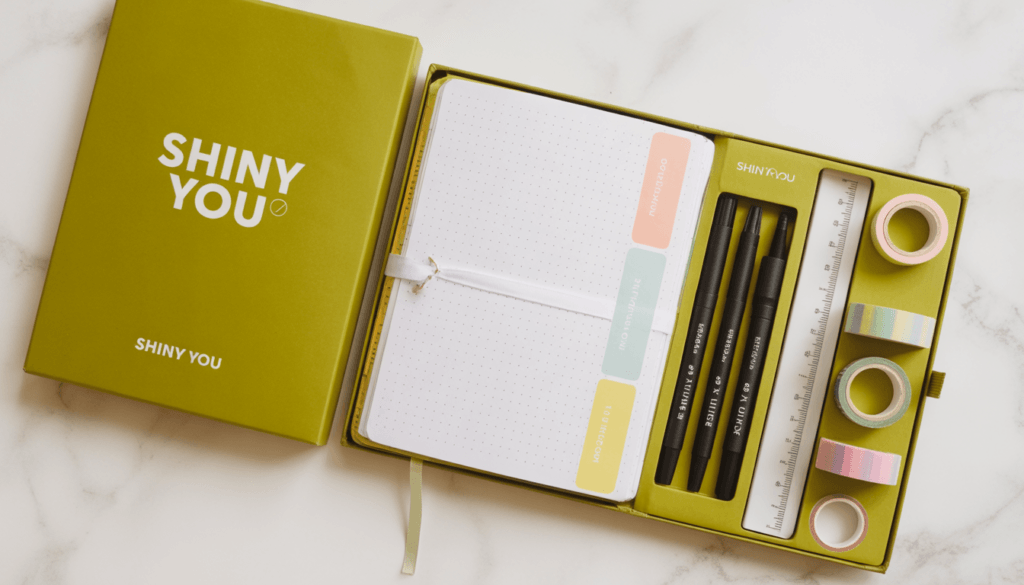 Bullet Journal Supplies: Complete List for 2026 4 Shiny You branded bulk bullet journal supplies kit with notebook fine liners highlighters and washi tape in olive gold packaging on white marble