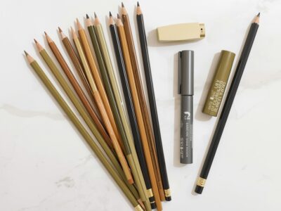 Art supplies set with pencils markers and colored pencils arranged on a white marble surface