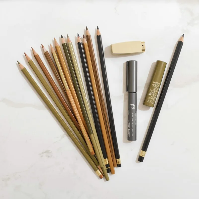 Art supplies set with pencils markers and colored pencils arranged on a white marble surface