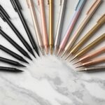 Home 89 Collection of gel ink pens in various colors including black pastel metallic and neon arranged in a flat lay on white marble