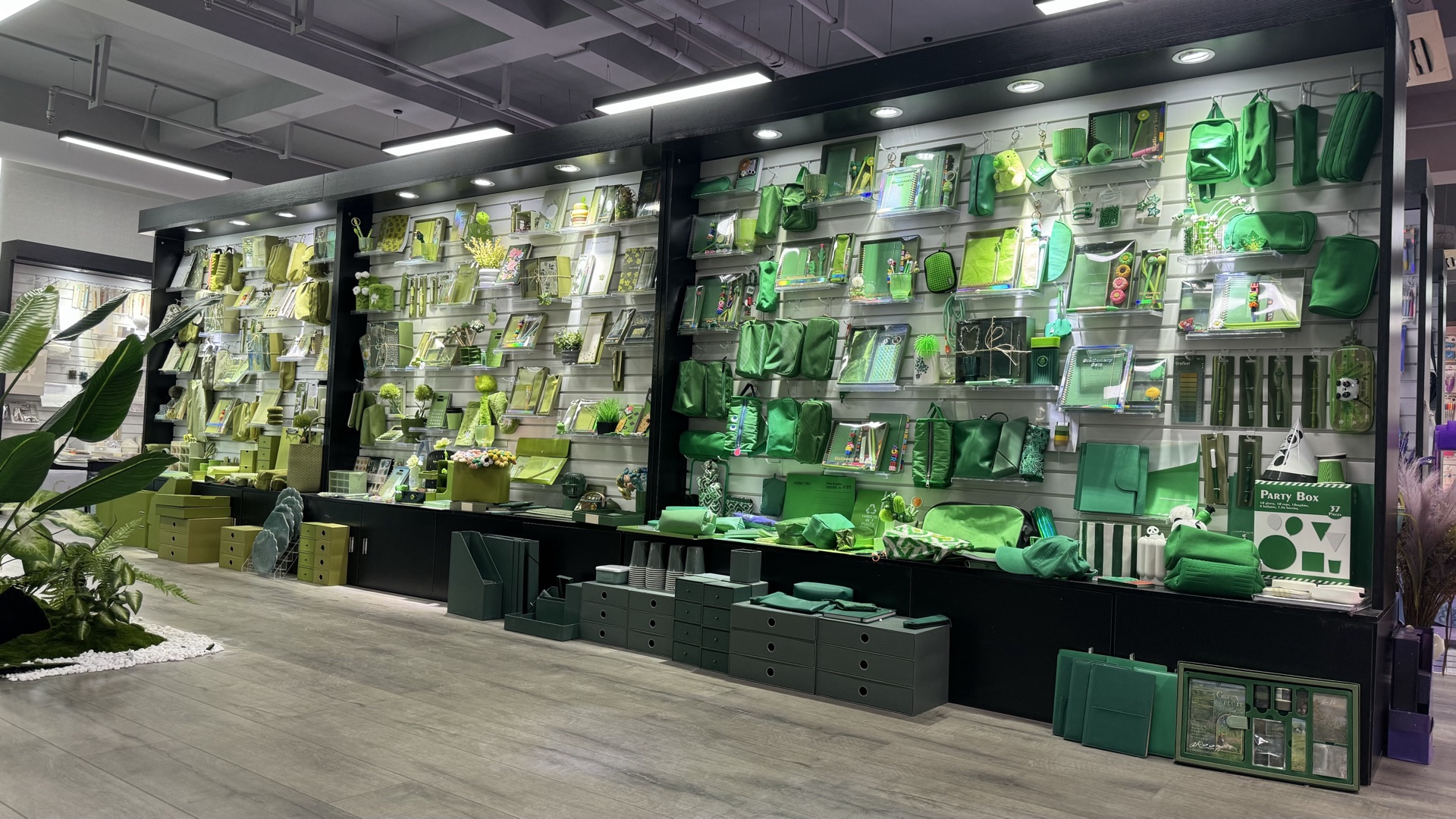 Green stationery, bags and related accessories displayed on a SHINYYOU showroom wall.